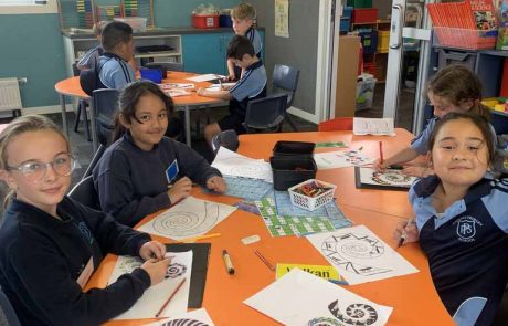 Papanui Primary students seated at an orange desk doing art